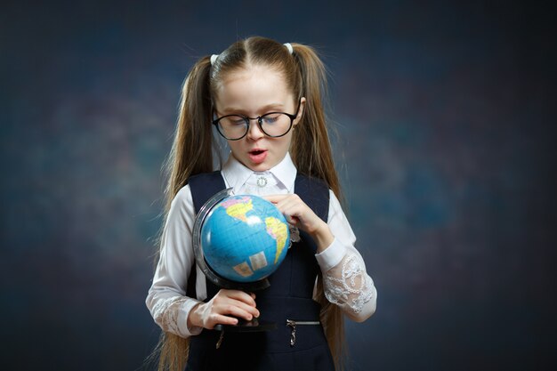 Bionda piccola scolaretta Hold World Globe in mano