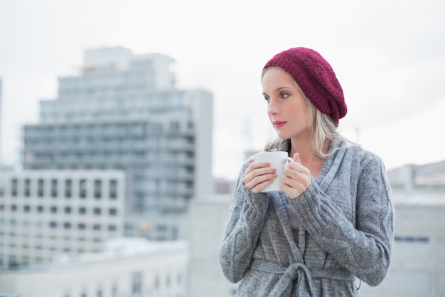 Bionda splendida di pensiero che beve caffè all&#39;aperto