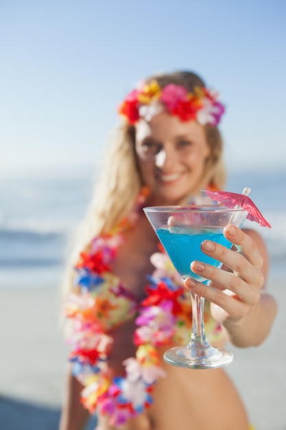 Bionda splendida in ghirlanda che tiene cocktail sulla spiaggia