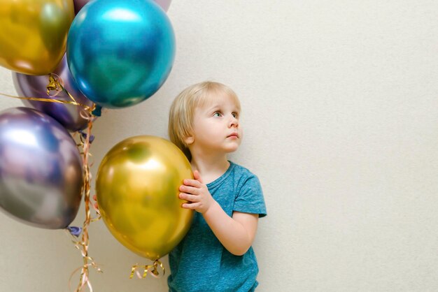 Biondo carino felice bambino bambino ragazzo festeggia il terzo compleanno con palloncini colorati a partyhome davanti wallbaby sorridente guardando la telecameraadorabile bambino caucasicodecorazione di sfondo festivo