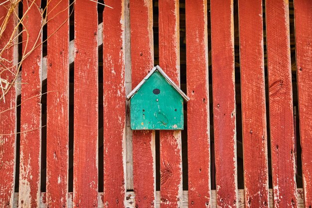 Birdhouse turchese sul lato del fienile rosso sbiadito