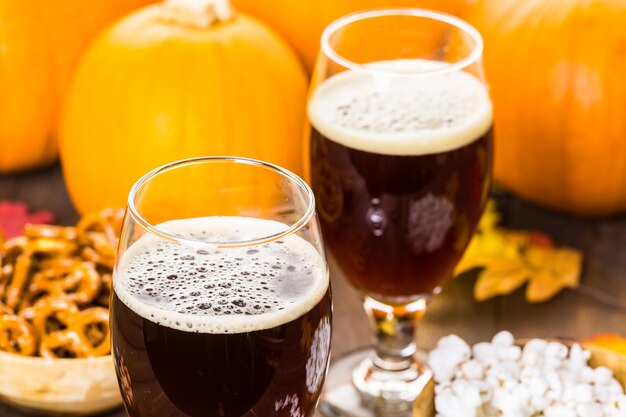 Birra artigianale alla zucca in bicchieri da birra con salatini salati e popcorn.