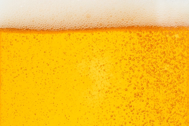 Birra di versamento con schiuma di bolle in vetro per lo sfondo