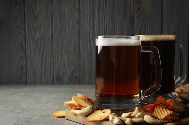 Birra e snack sul tavolo grigio contro la parete in legno