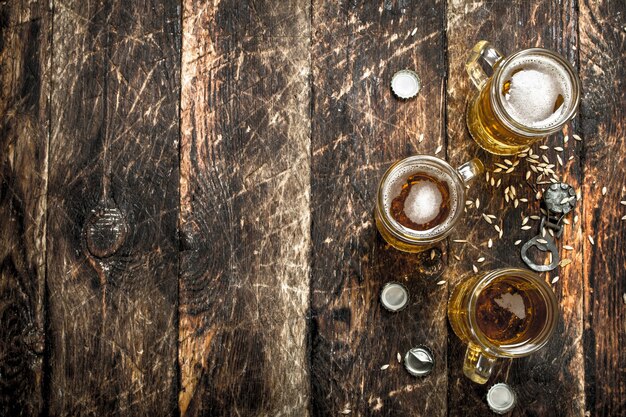 Birra fresca in un bicchiere con tappi e apribottiglie. su uno sfondo di legno.