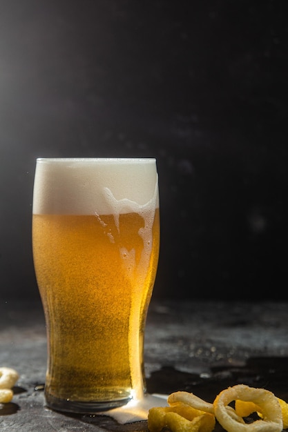 Birra leggera in un bicchiere su uno sfondo scuro