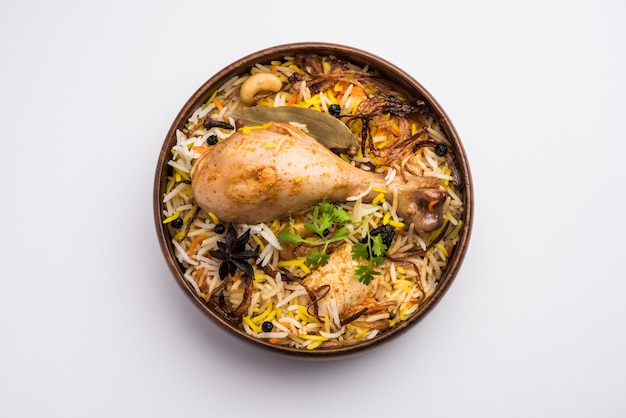 Biryani di pollo piccante in stile ristorante in una ciotola di legno con Raita e salan, cibo popolare indiano o pakistano