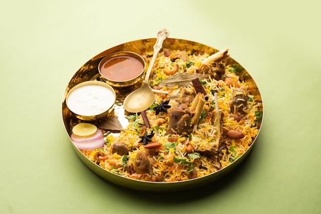 Biryani indiano di montone preparato con riso basmati servito con salsa di yogurt su sfondo lunatico, messa a fuoco selettiva