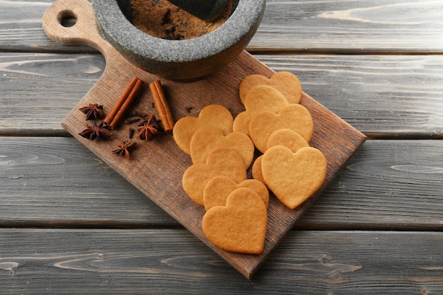 Biscotti a forma di cuore e cannella sul tagliere, vista dall'alto