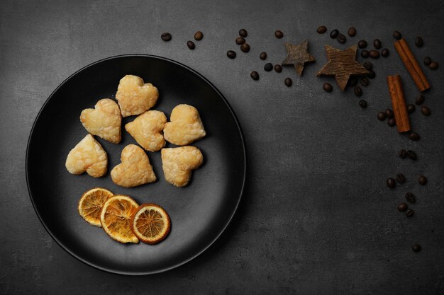 Biscotti a forma di cuore in padella con spezie essiccate su sfondo grigio scuro