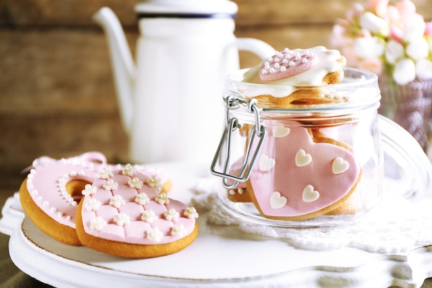 Biscotti a forma di cuore per San Valentino e teiera su fondo di legno