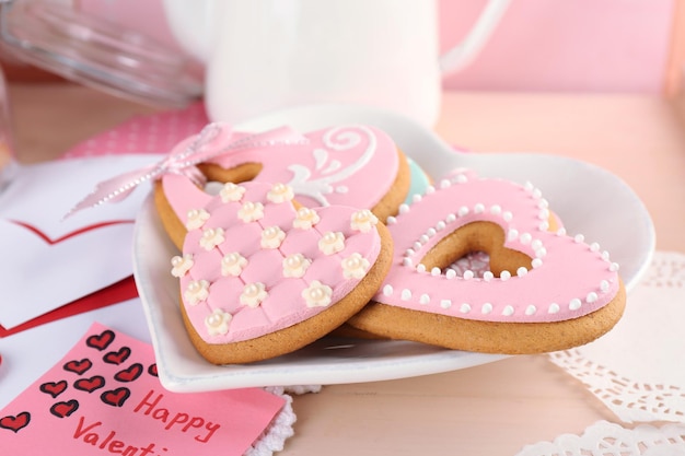 Biscotti a forma di cuore per San Valentino su piastra, su fondo in legno colorato