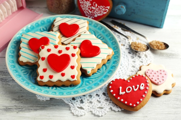 Biscotti a forma di cuore per San Valentino su piastra, su fondo in legno colorato