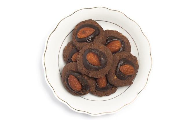 biscotti afghani fatti di cioccolato e cornflakes con mandorle in cima in una piccola piastra bianca vista superiore isolata su un percorso di ritaglio sullo sfondo bianco