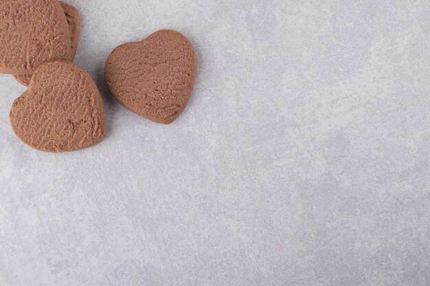 Biscotti al cioccolato a forma di cuore posti su un tavolo di pietra.