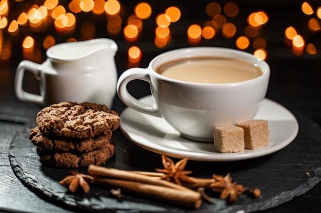 Biscotti al cioccolato, caffè, spezie su luci di Natale offuscate.