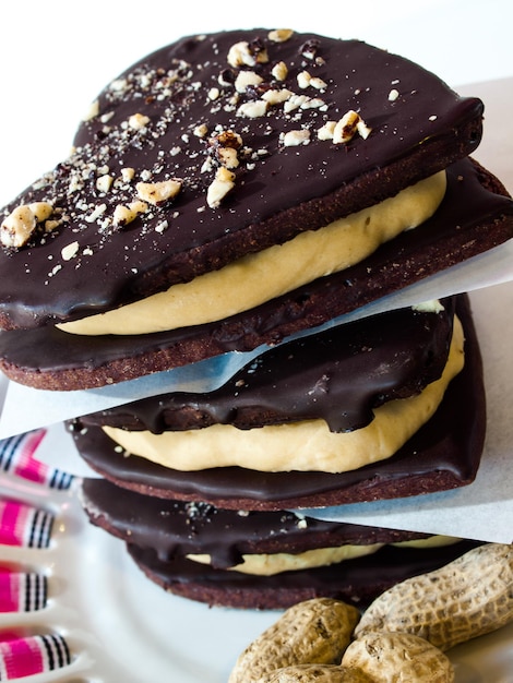 Biscotti al cioccolato con ripieno di burro di arachidi su sfondo bianco.