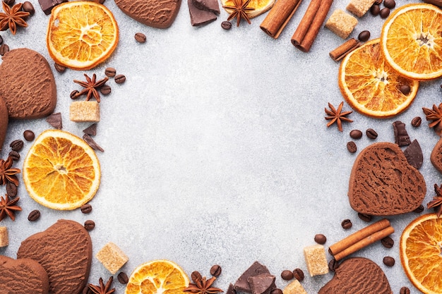 Biscotti al cioccolato cuore, arance cannella e spezie piccanti su un tavolo grigio, vista dall'alto, copia dello spazio.