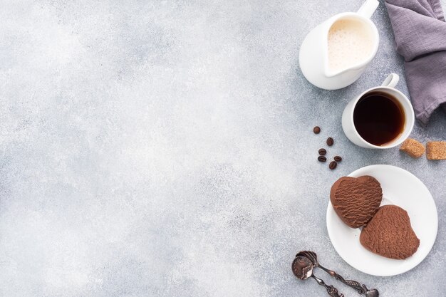 Biscotti al cioccolato cuore e una tazza di caffè nero con latte sul tavolo, vista dall'alto. Copia spazio.