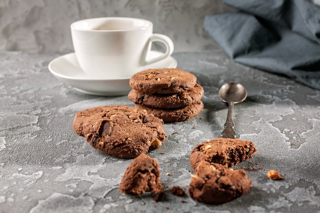 Biscotti al cioccolato e una tazza di caffè su uno sfondo grigio cemento.