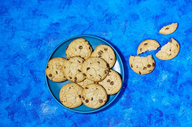 biscotti al cioccolato fatti in casa in piatto su uno sfondo grunge blu.