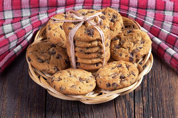 Biscotti al cioccolato in un piatto di vimini su un tavolo di legno e una tovaglia rossa