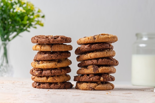 Biscotti al cioccolato. Sfondo con brocca di fiori sfocati e latte.