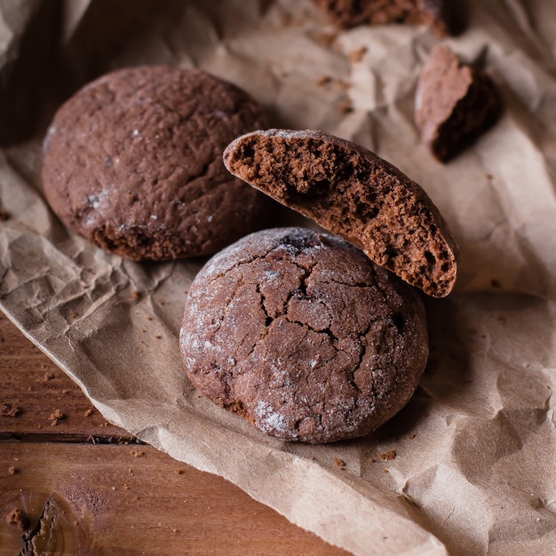 Biscotti al cioccolato su carta sul fondo della tavola in legno. Snack dolce. Copia spazio