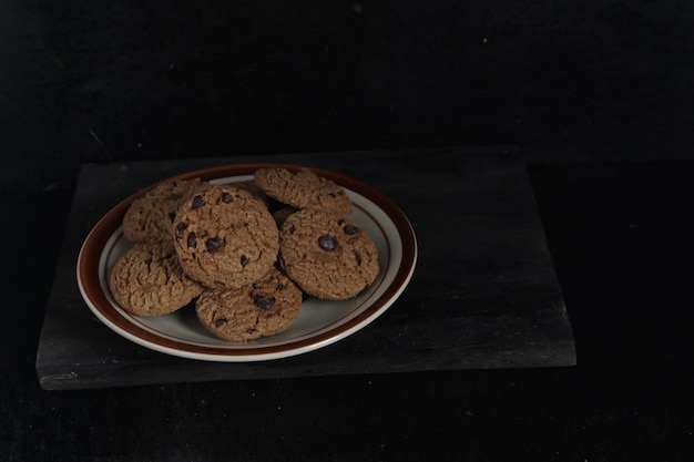 Biscotti al cioccolato sulla piastra su sfondo nero