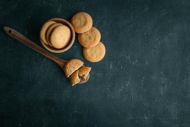 Biscotti al pane corto con riempimento di cioccolato su un dolce di fondo a cucchiaio di legno