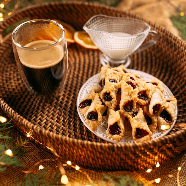 Biscotti alla marmellata con caffè e latte su un cesto con rami di abete e garldan