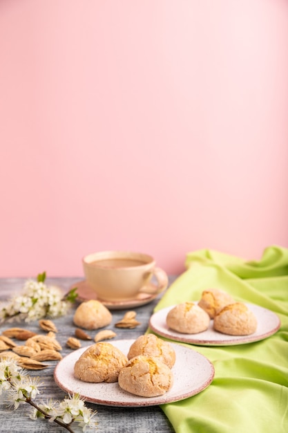 Biscotti alle mandorle e una tazza di caffè su una superficie grigia e rosa e tessuto di lino verde