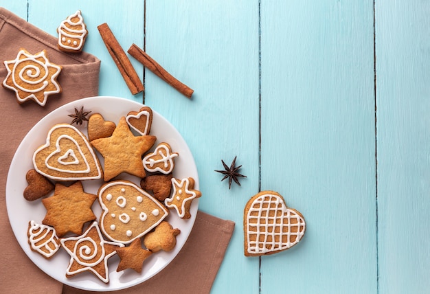 Biscotti allo zenzero decorati con glassa su un piatto su un fondo di legno blu