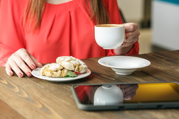 Biscotti allo zenzero e mani della donna che tengono una tazza di caffè Concetto di pausa caffè Tablet su un tavolo