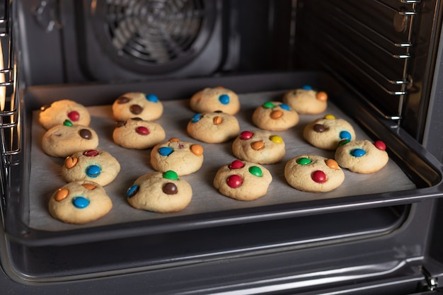 Biscotti appena sfornati con dolci di colore in forno