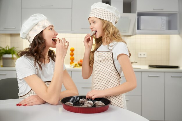 Biscotti attraenti dell'assaggio della bambina e della madre alla cucina