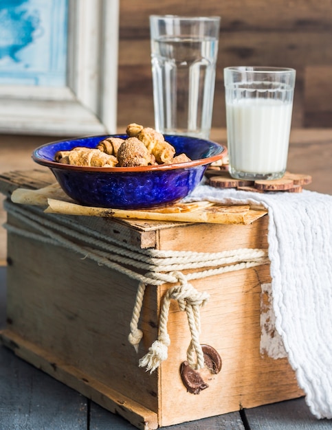 Biscotti bagel da una pasta frolla con ripieno, latte, nel piatto blu pasticceria dolce su un legno