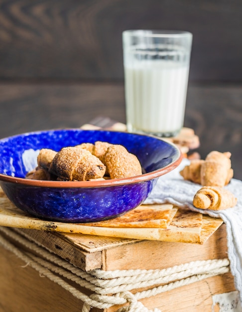 Biscotti bagel da una pasta frolla con ripieno, latte, nel piatto blu pasticceria dolce su un legno