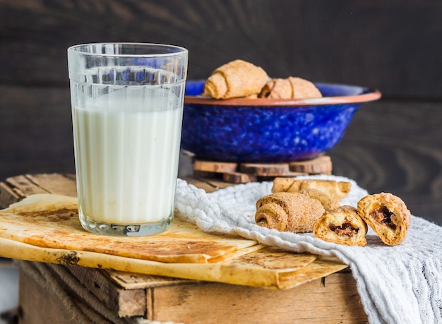 Biscotti bagel da una pasta frolla con ripieno, latte, nel piatto blu pasticceria dolce su un legno