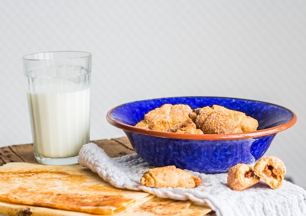 Biscotti bagel da una pasta frolla con ripieno, latte, nel piatto blu pasticceria dolce su un legno