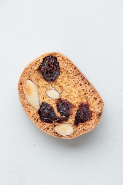 Biscotti cantucci con mandorle e mirtilli rossi su sfondo bianco vista dall'alto