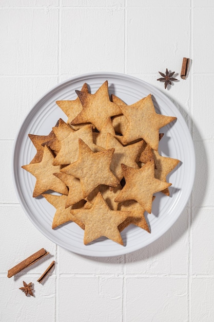 Biscotti con cannella sotto forma di stelle su un piatto su un fondo bianco per il nuovo anno