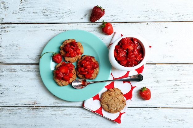 Biscotti con fragole fresche in piatto sulla vista del piano d'appoggio in legno