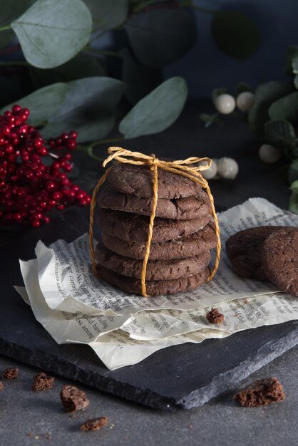 Biscotti con gocce di cioccolato impilati e legati con spago su pagine squallide adagiati su una pietra nera