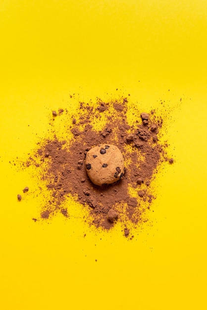 Biscotti con gocce di cioccolato su fondo giallo con una spruzzata di cacao