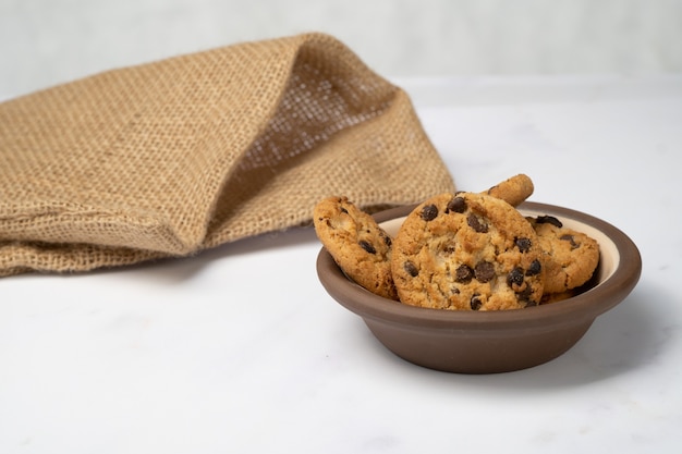 biscotti con gocce di cioccolato su un piatto di argilla con un sacchetto di tela dietro bur