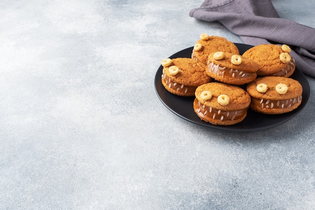 Biscotti con pasta di crema a forma di mostri per la festa di Halloween. Divertenti facce fatte in casa fatte di biscotti di farina d'avena e latte condensato bollito. copia spazio