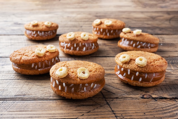 Biscotti con pasta di crema a forma di mostri per la festa di Halloween. Divertenti facce fatte in casa fatte di biscotti di farina d'avena e latte condensato bollito.