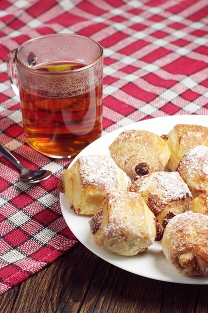 Biscotti con uvetta nel piatto e tazza da tè sulla tovaglia rossa nascosta da tavola