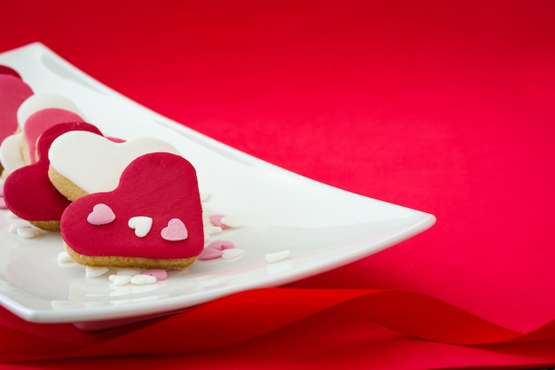 Biscotti del biglietto di S. Valentino con forma del cuore su rosso